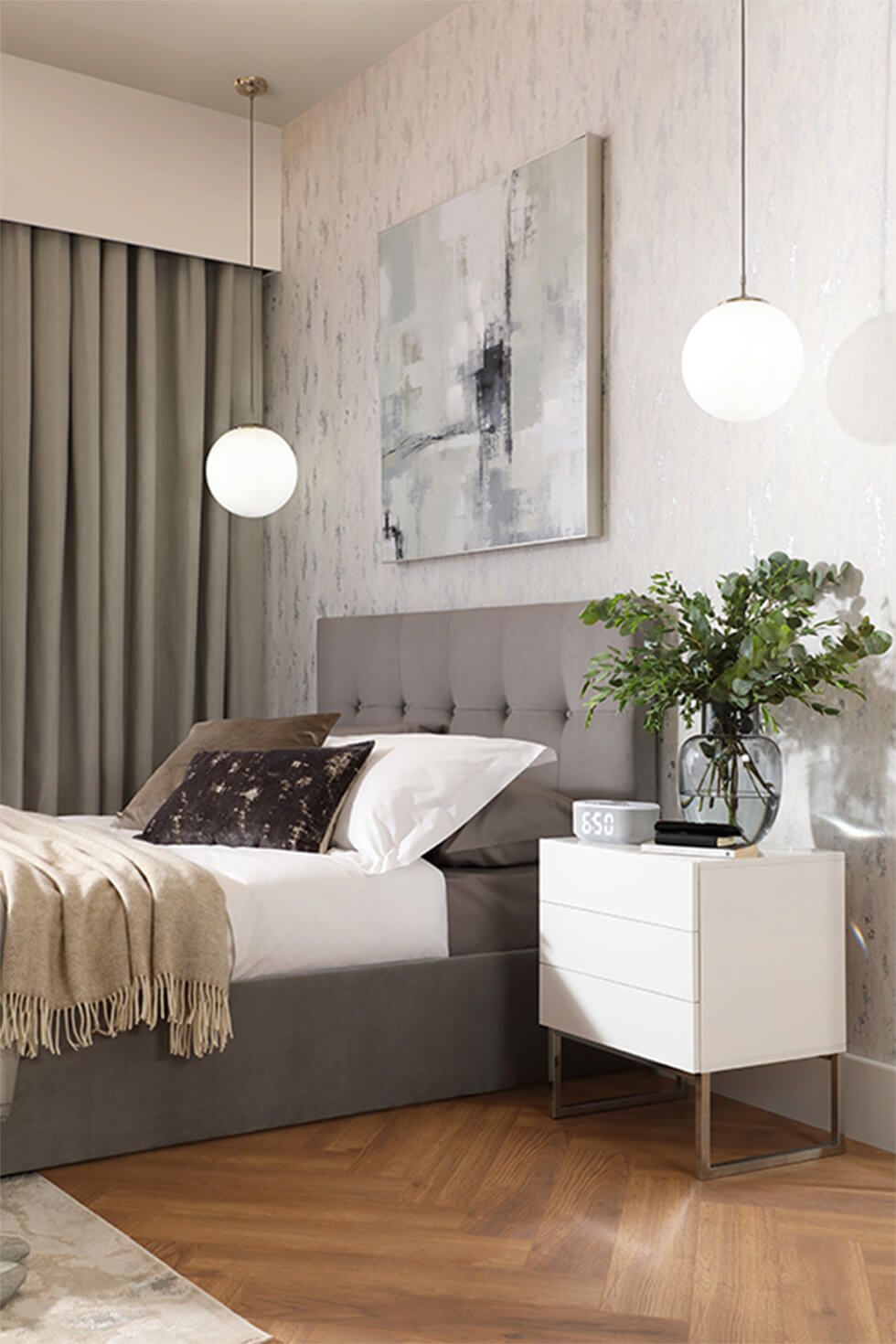 Bedroom with a tufted grey bed, pendants lamps and a white side table